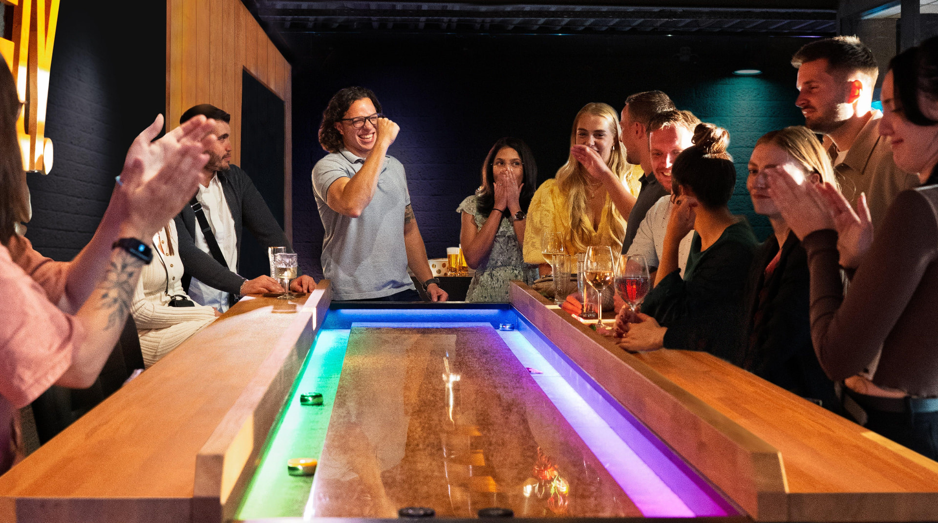 Guests playing on an illuminated shuffleboard table in a premium bar